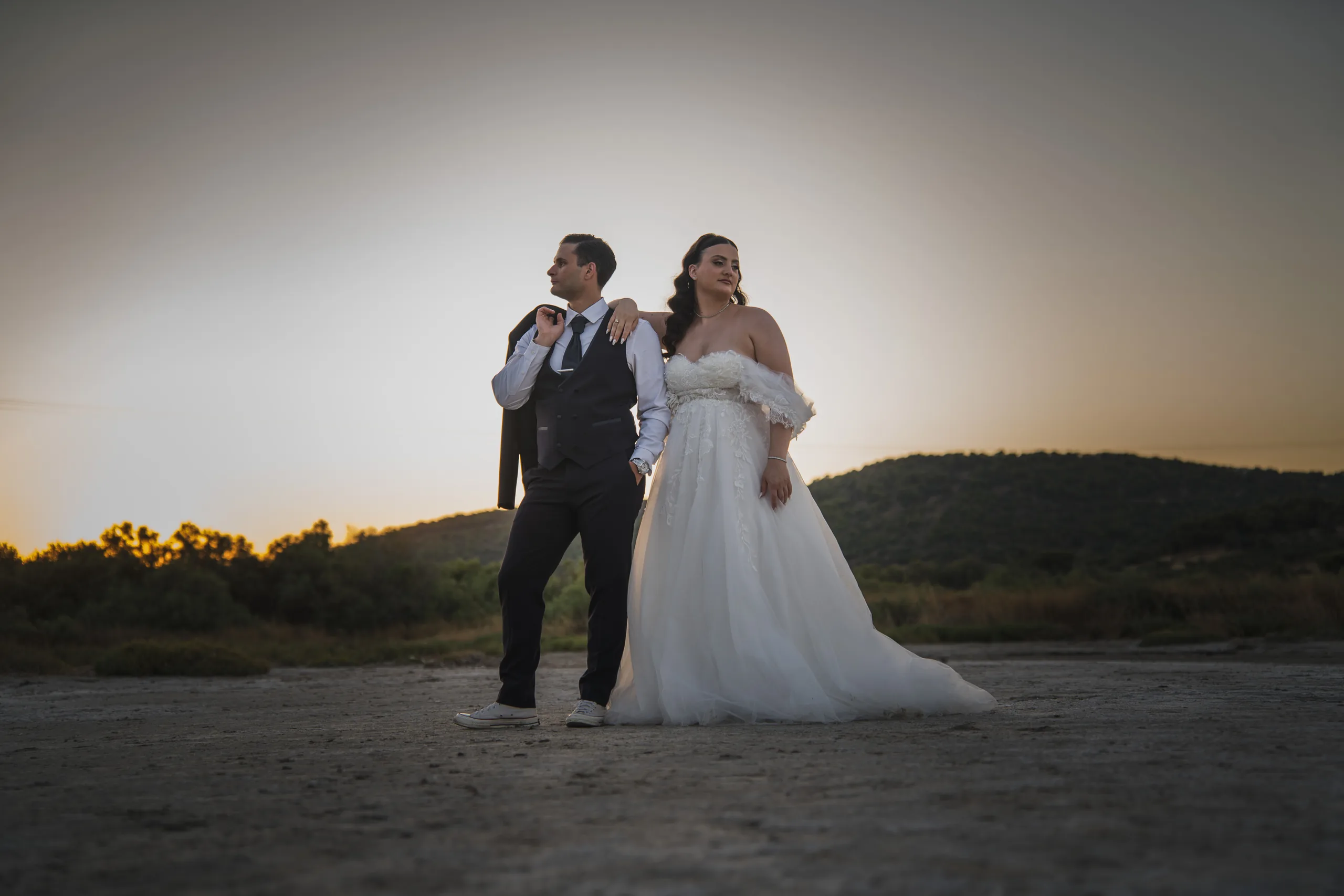 The couple on the shore at sunset, the groom's jacket over his shoulder
