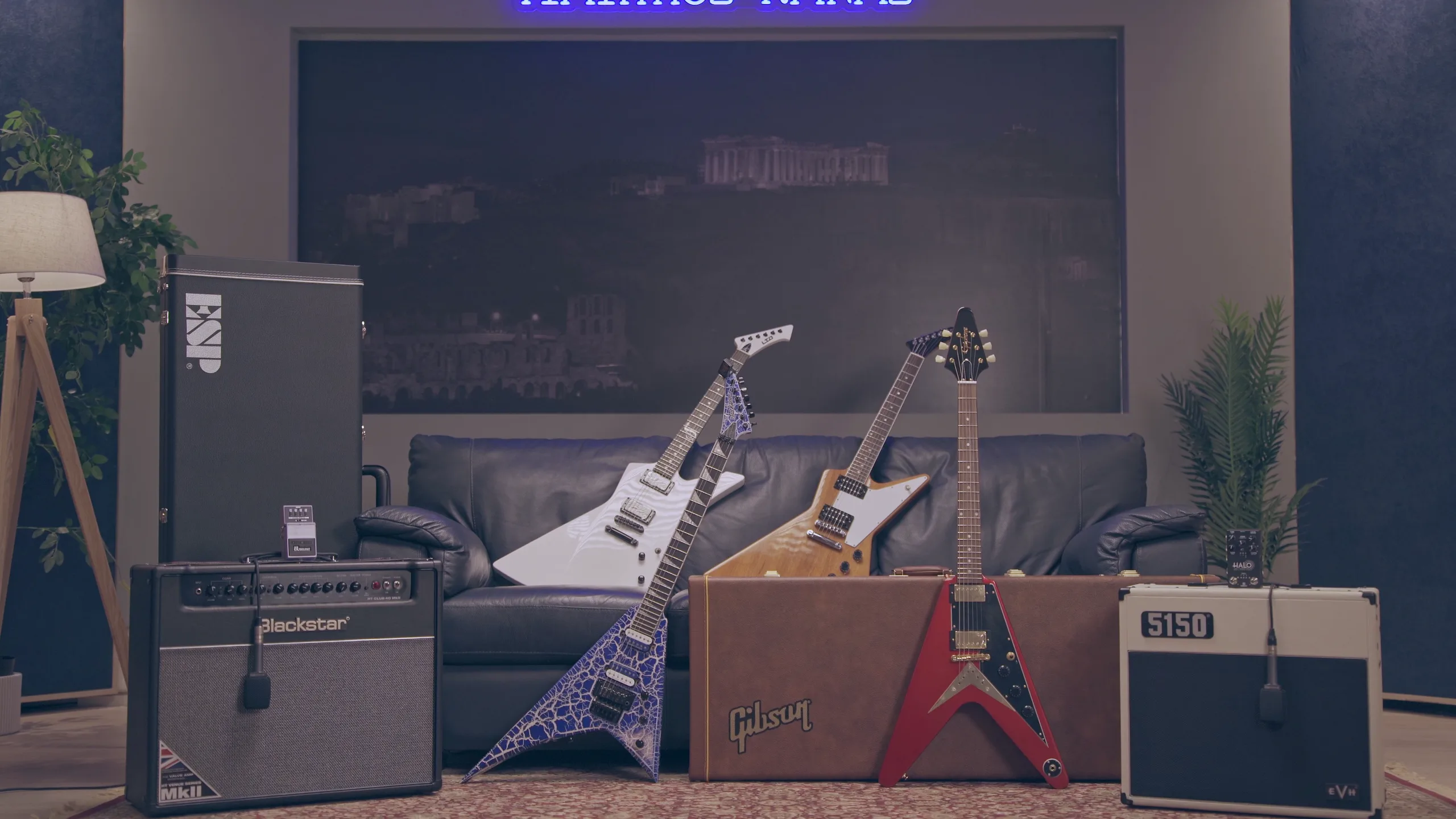 Electric guitars and amplifiers set up in a studio in front of a leather sofa