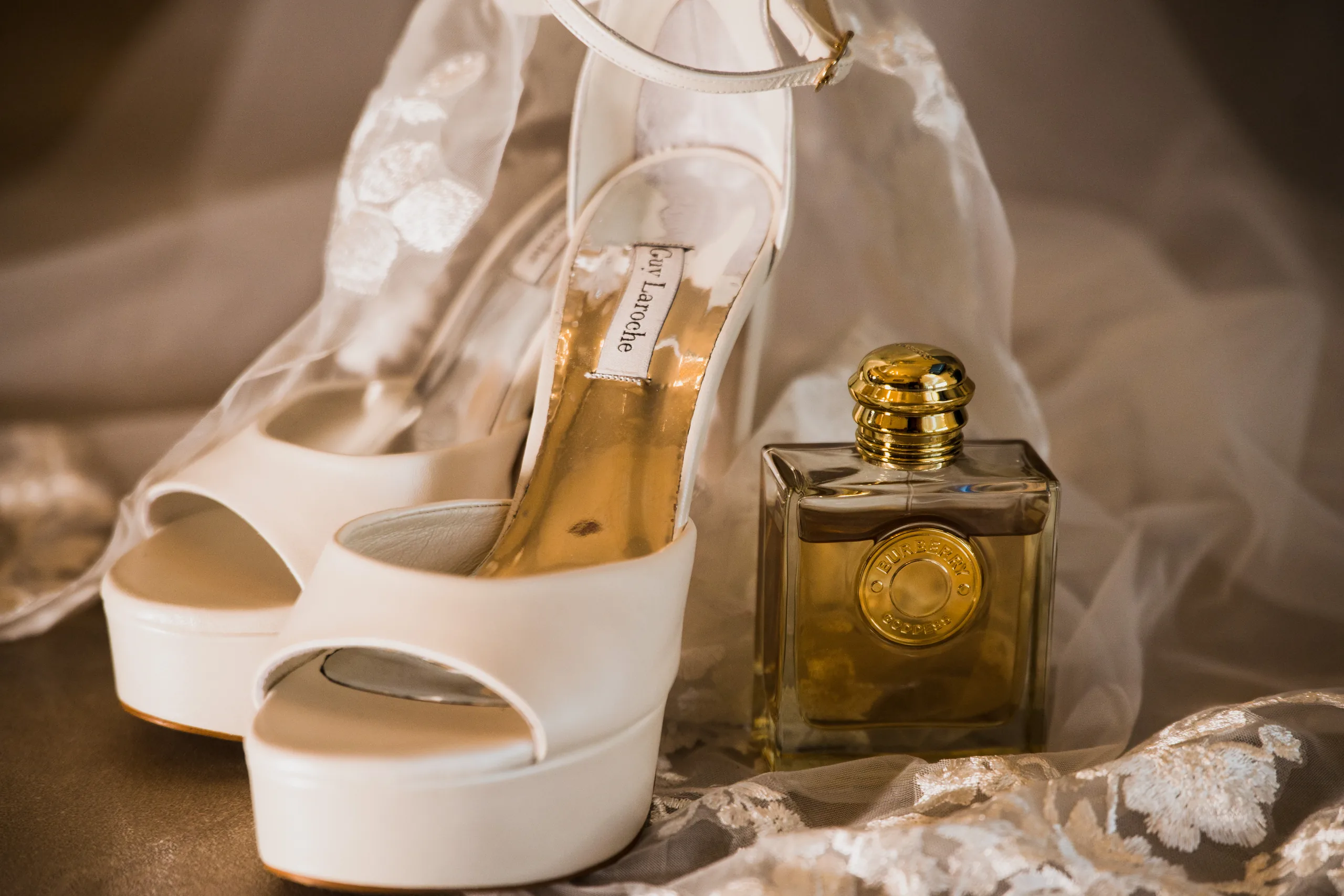The bride's shoes and perfume resting on lace