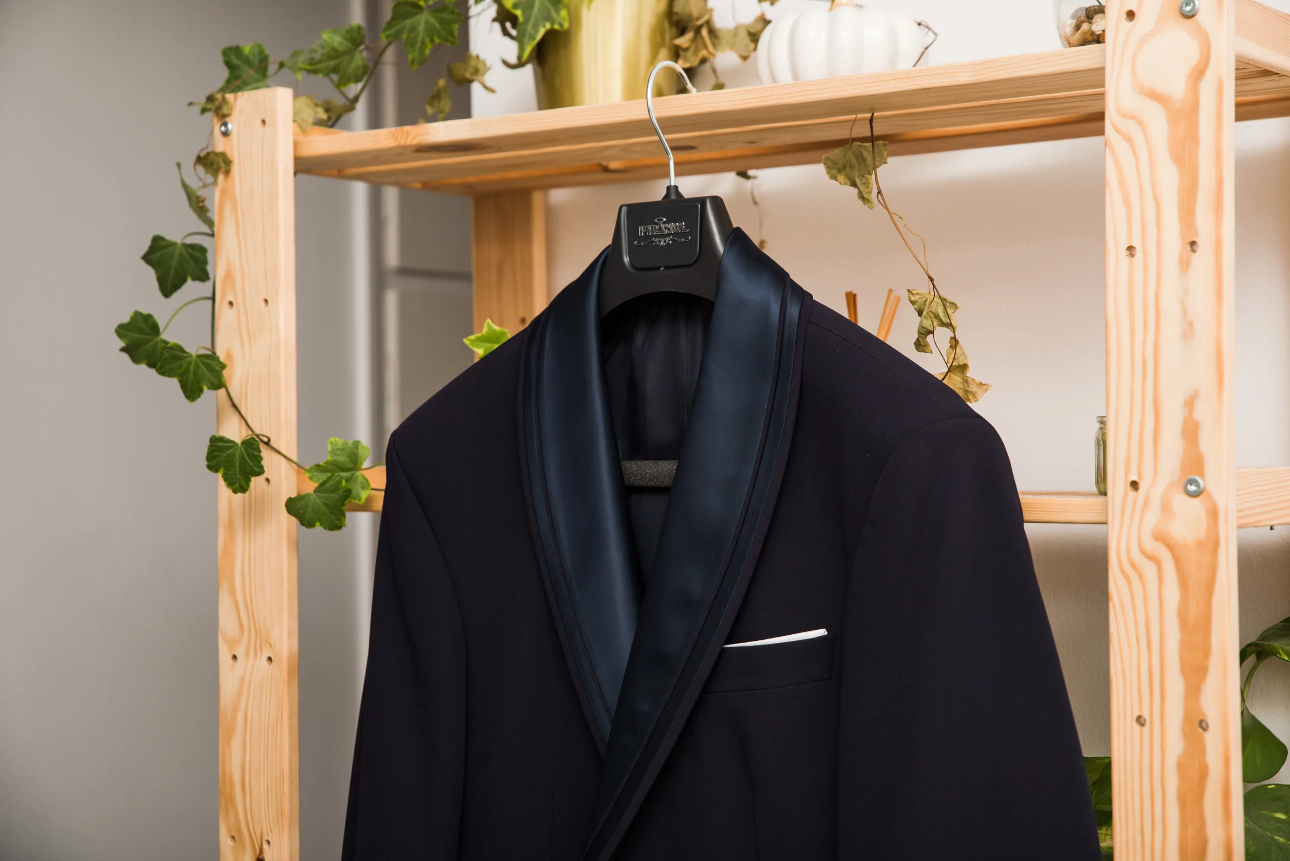 The groom's navy jacket hanging on a wooden rack