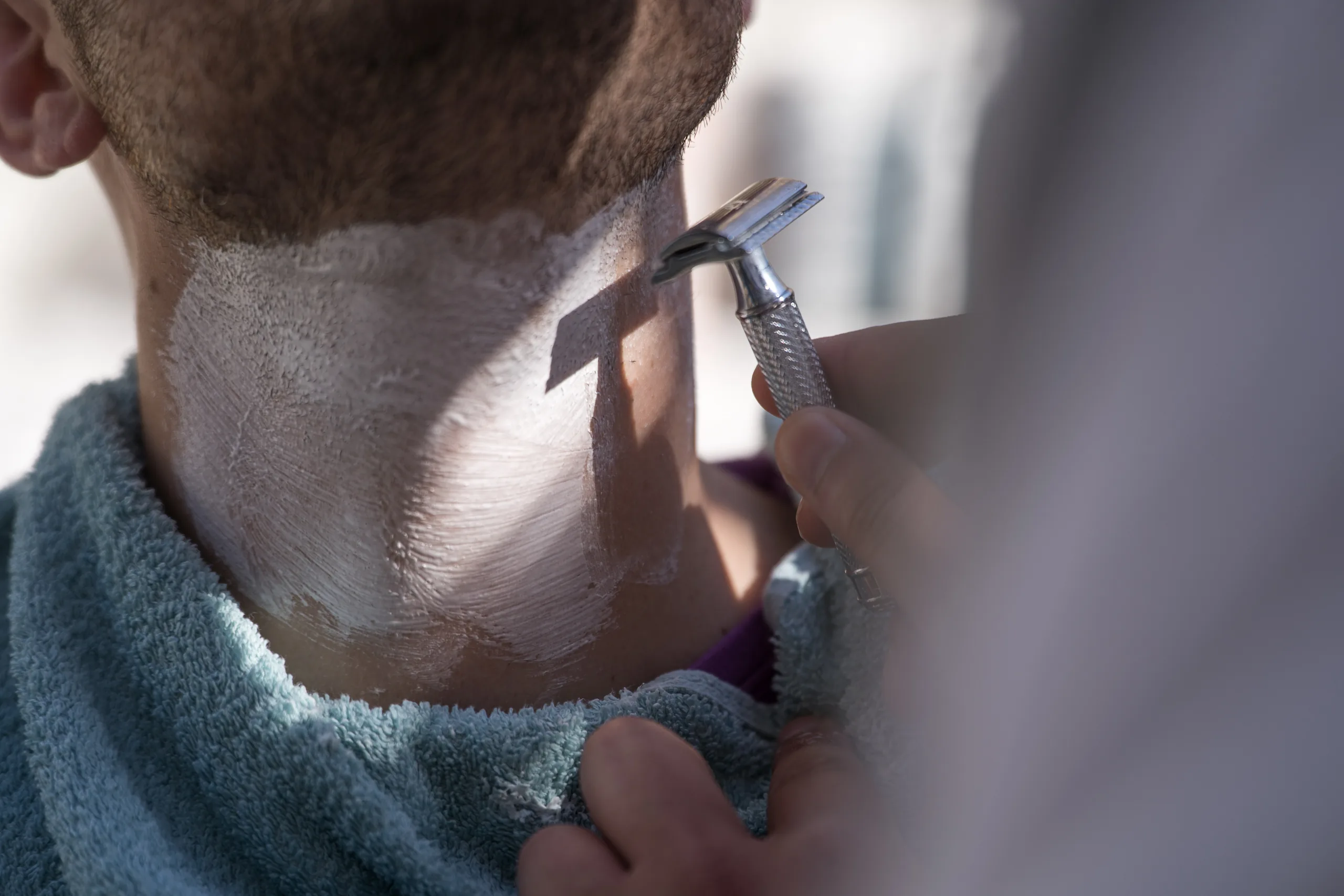 Close-up of the groom being shaved with a straight razor