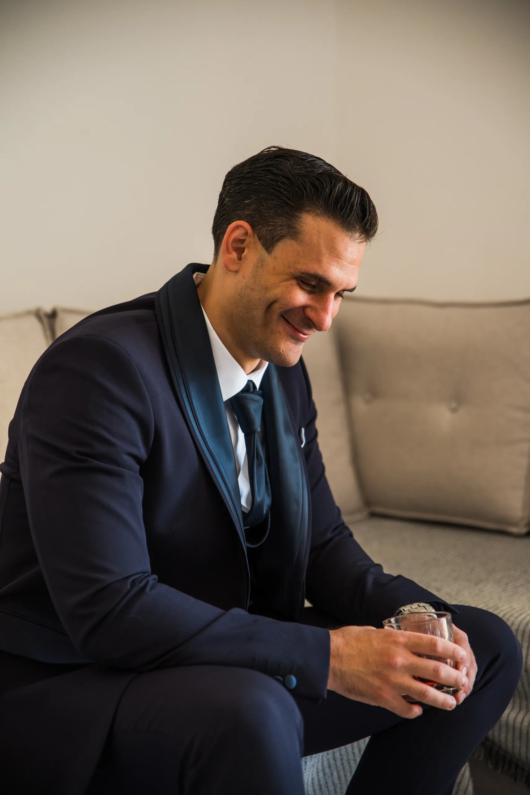 The groom smiling in his navy suit