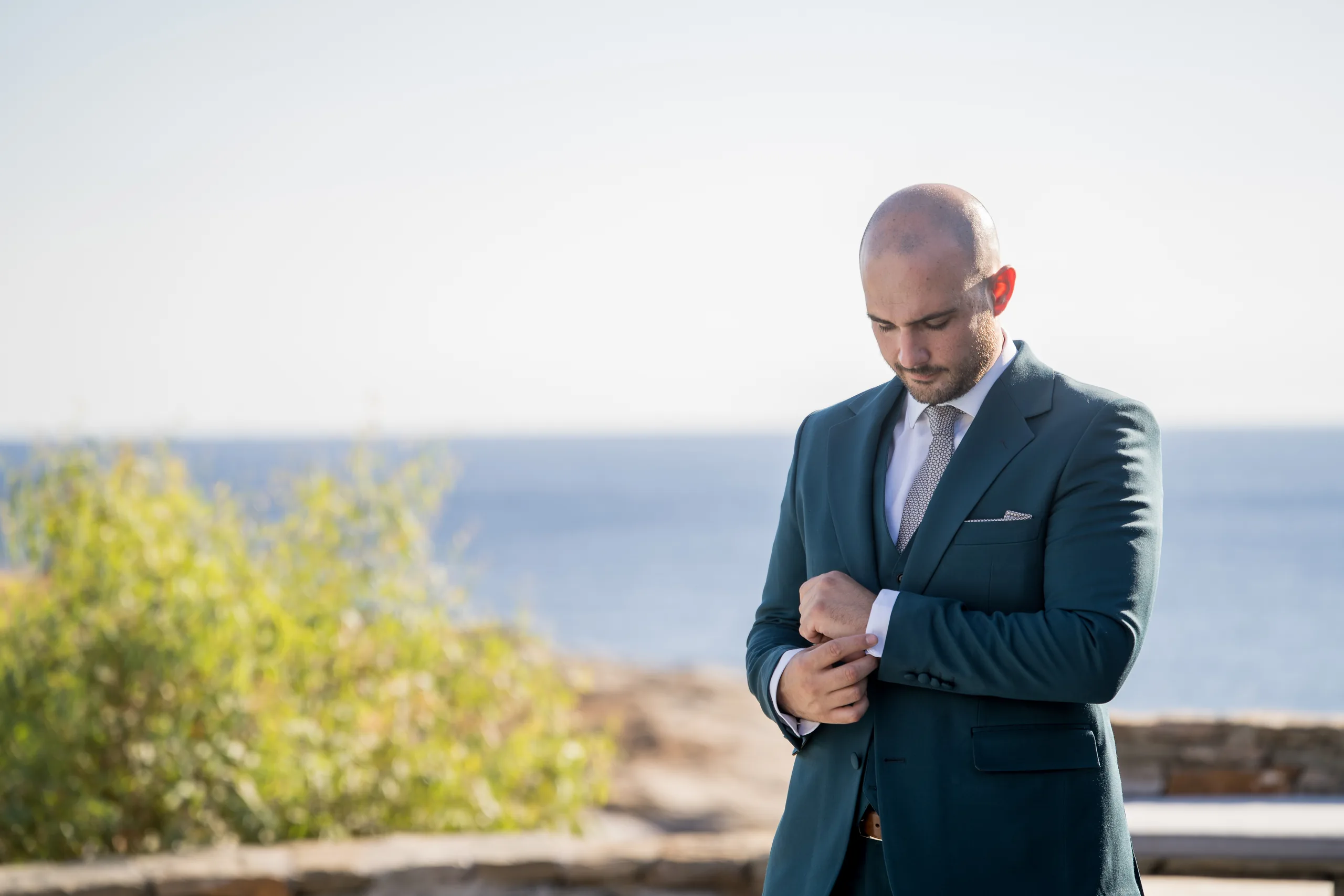 The groom fastening his cuffs by the sea