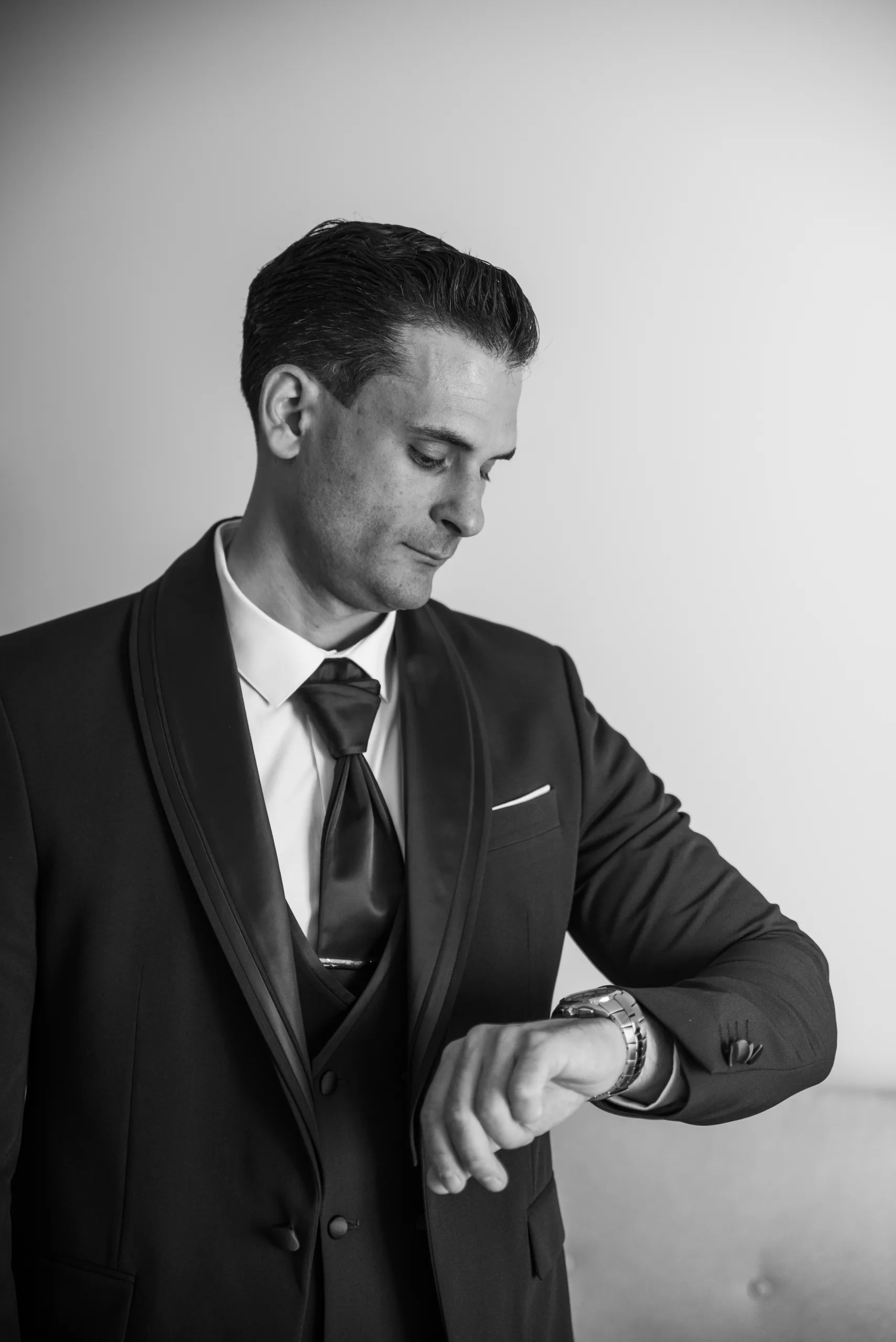 Black-and-white photo of the groom fastening his watch