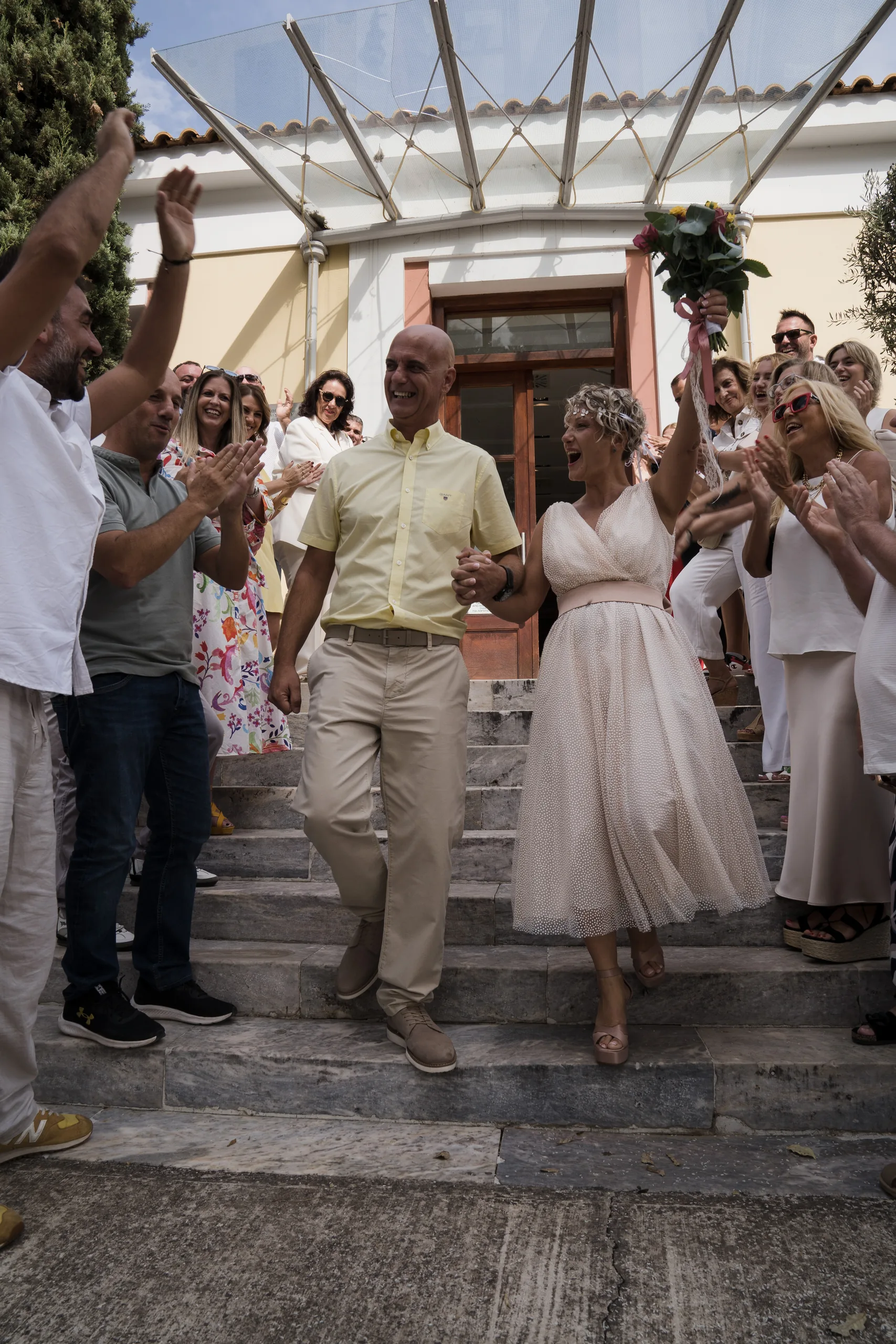 Οι καλεσμένοι ρίχνουν ρύζι καθώς το ζευγάρι κατεβαίνει τα σκαλιά