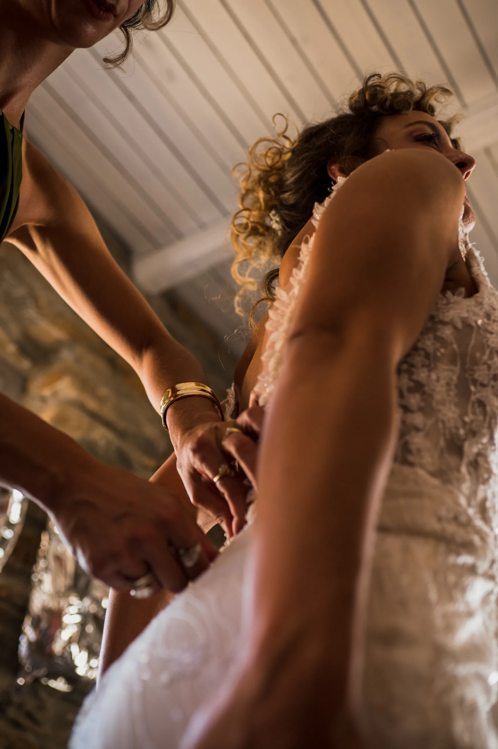The bride's dress being fastened at the back