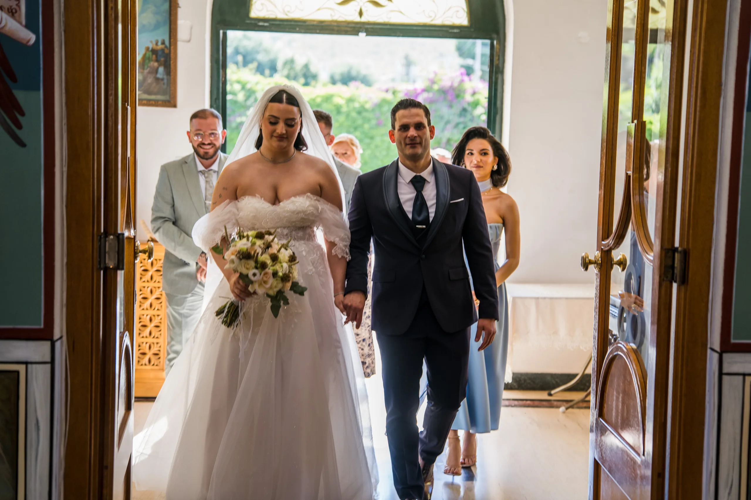 The bride and groom walk into the church hand in hand