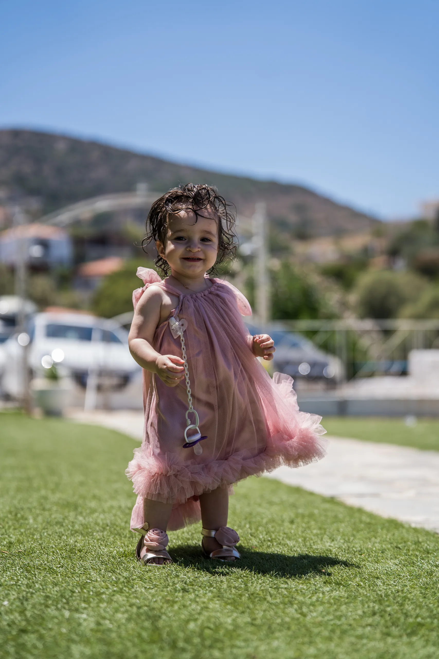 Η Φωτεινή όρθια στο γρασίδι με το ροζ φόρεμά της