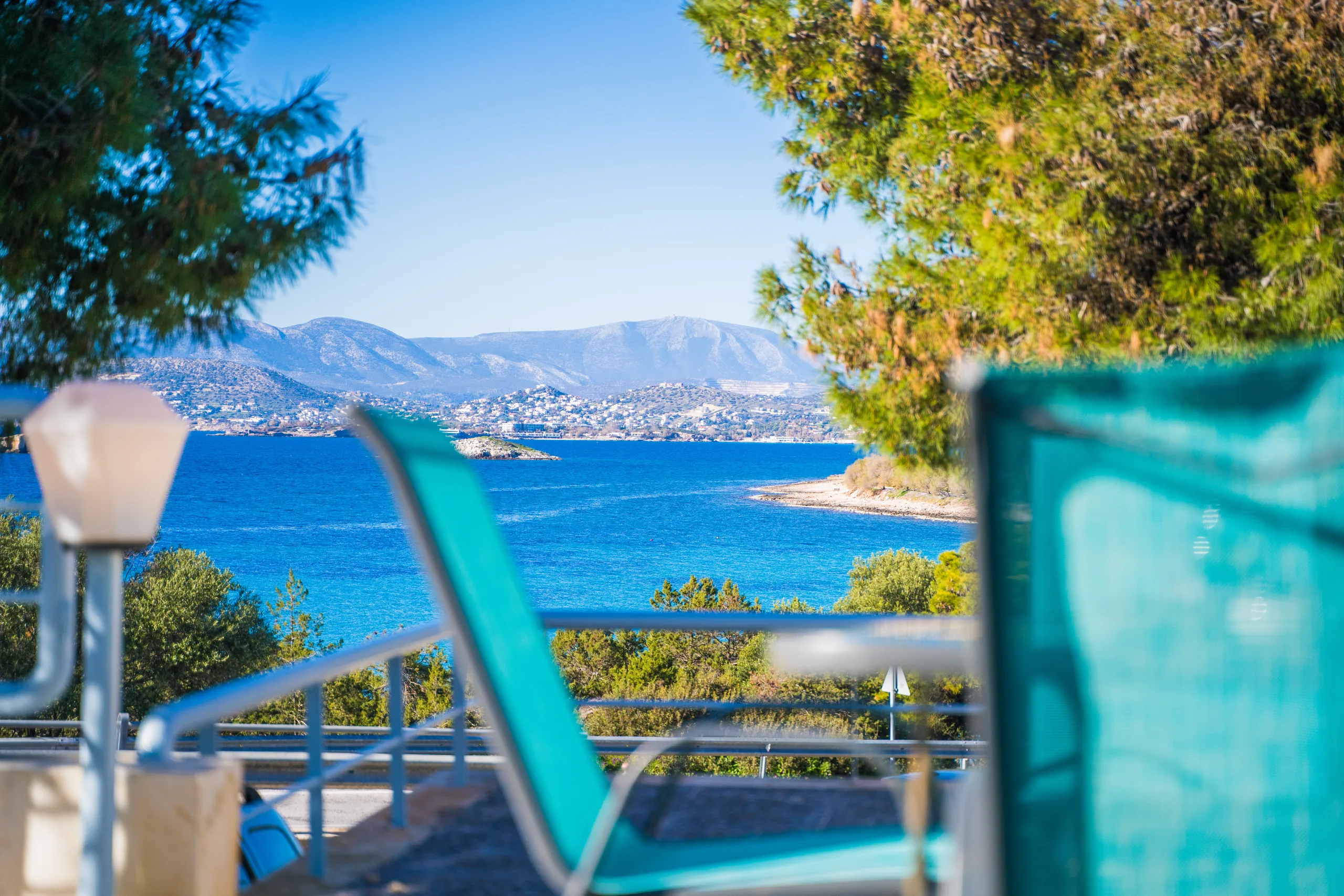 Μια καρέκλα στο μπαλκόνι με θέα στον κόλπο μέσα από τα πεύκα