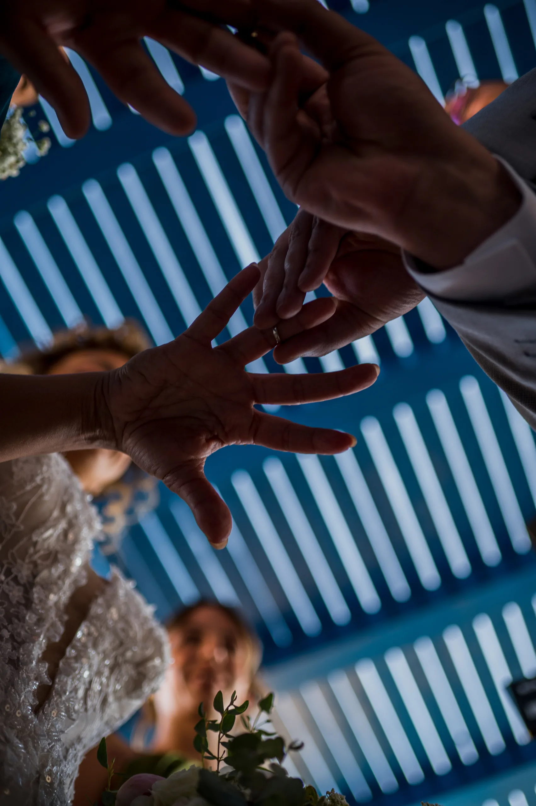 Hands reaching over the couple to exchange the rings