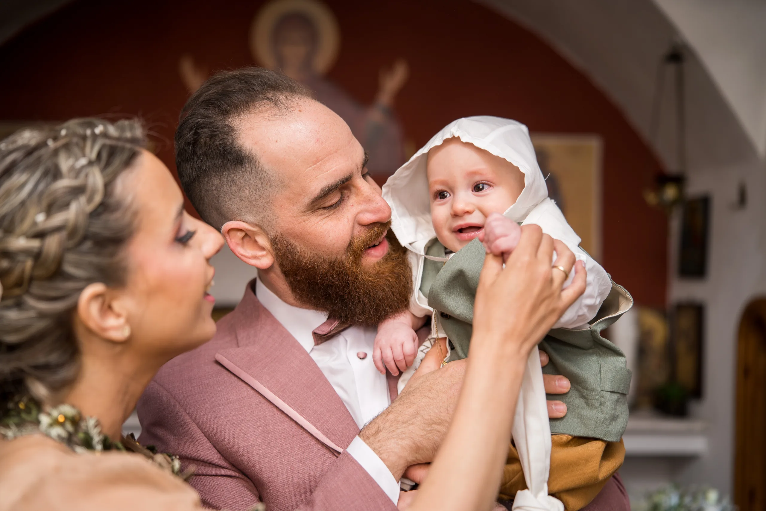 The couple laughing with their baby in the church