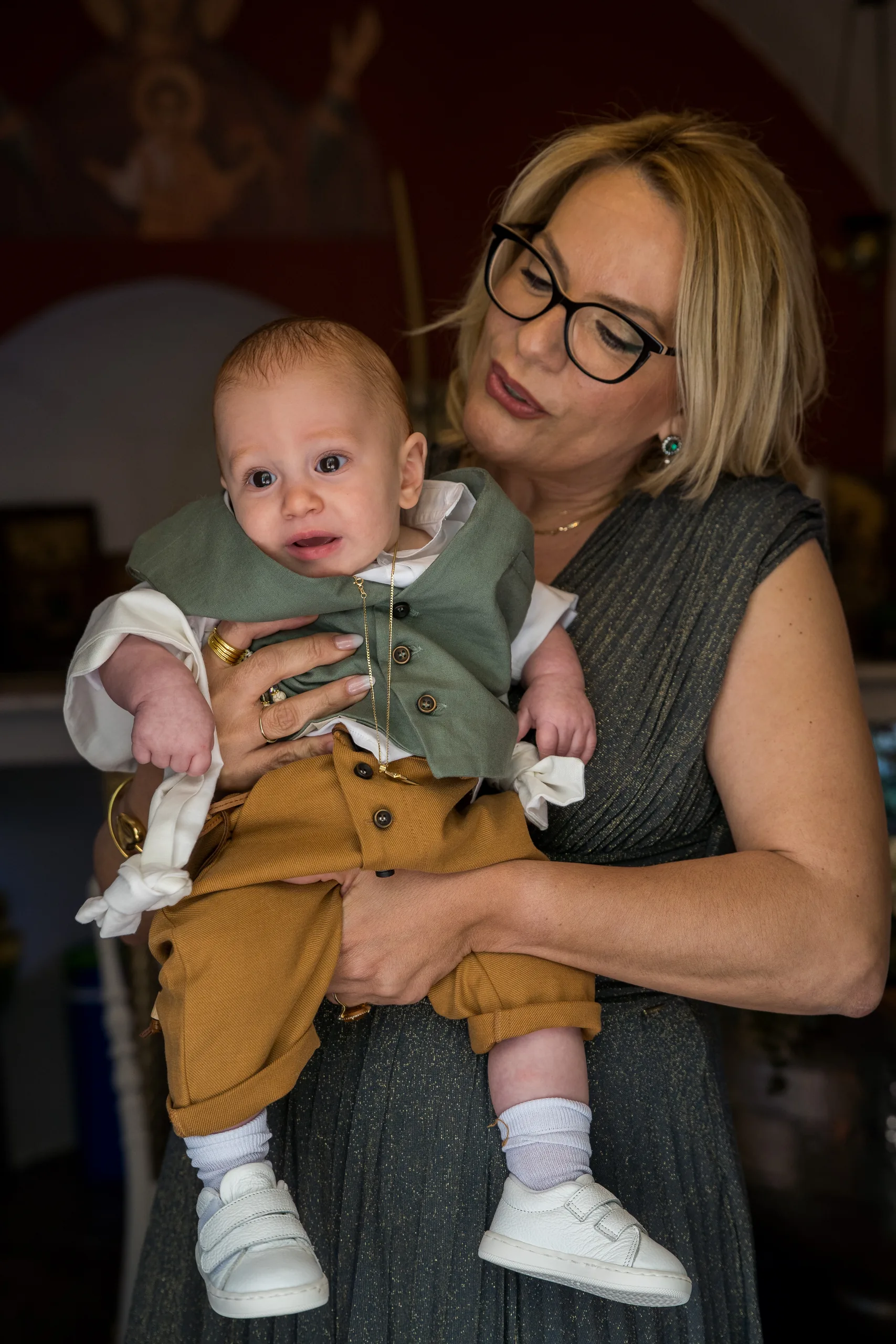 A woman holding the baby in his baptism clothes