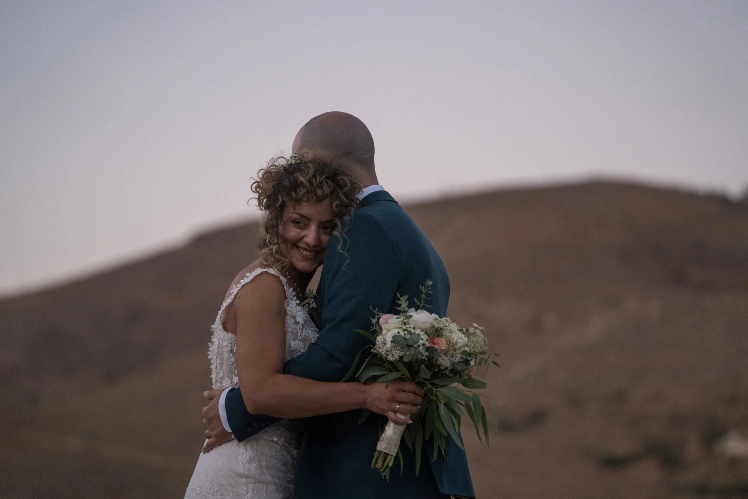 The couple embracing on a hillside at dusk
