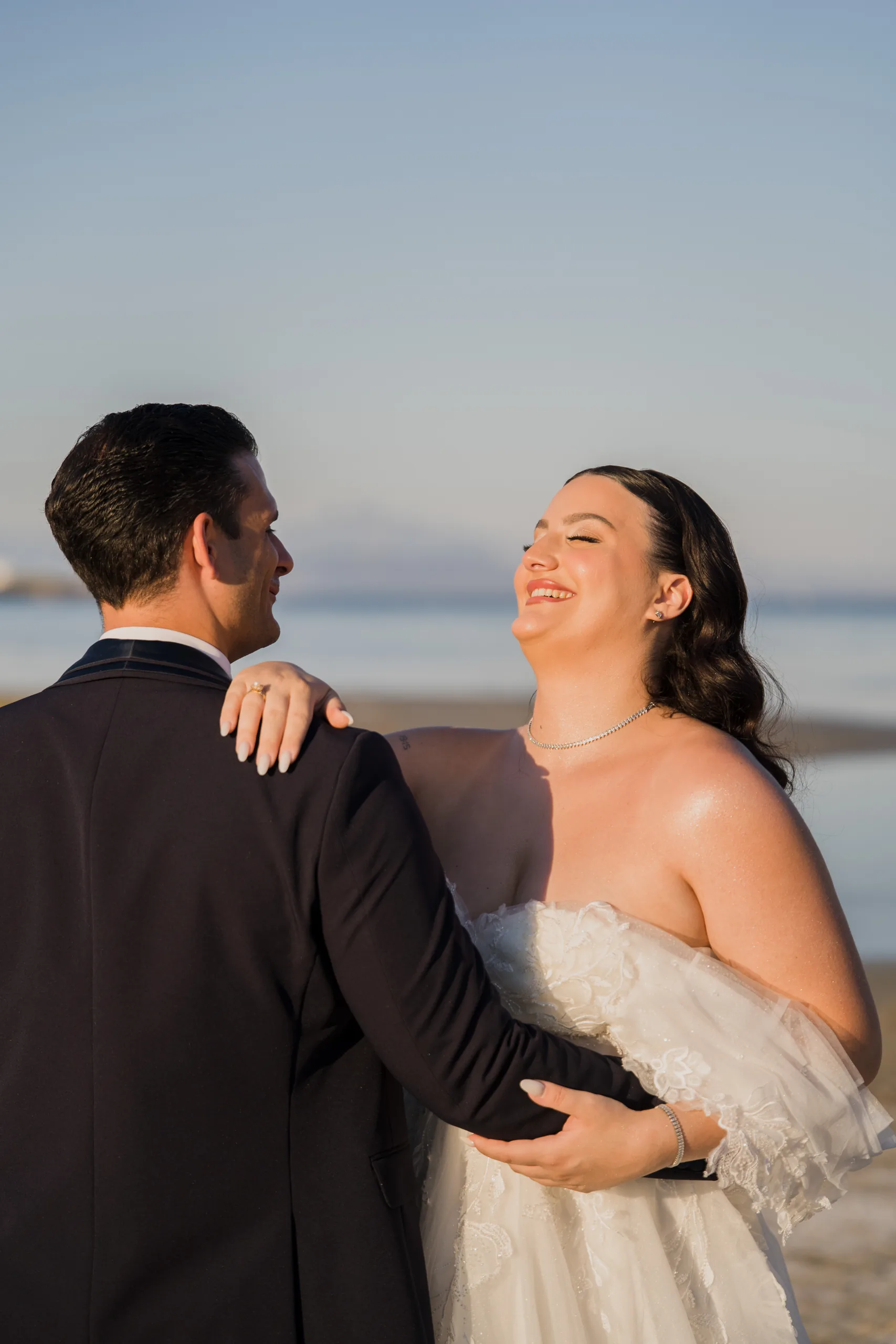 The bride laughing in the groom's arms by the sea