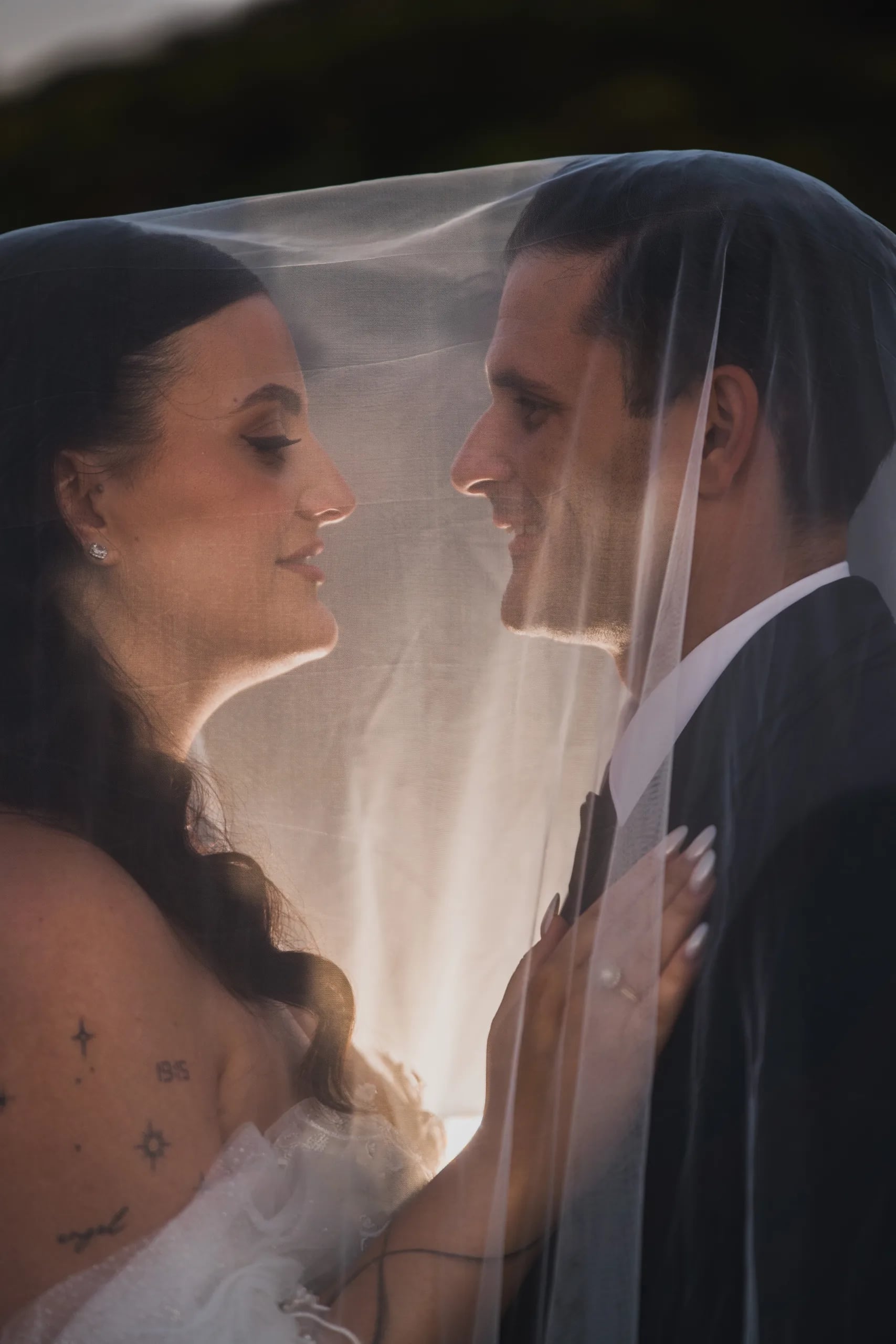 The couple face to face beneath the bride's veil