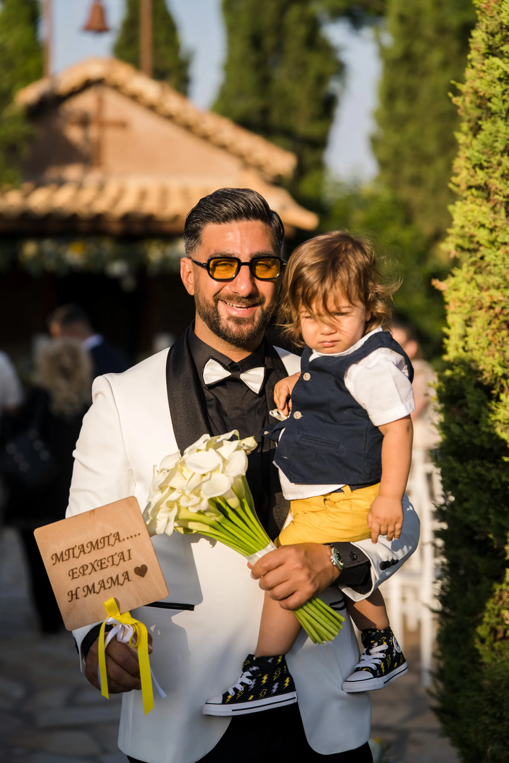 Ο γαμπρός κρατά ένα αγοράκι και την ανθοδέσμη