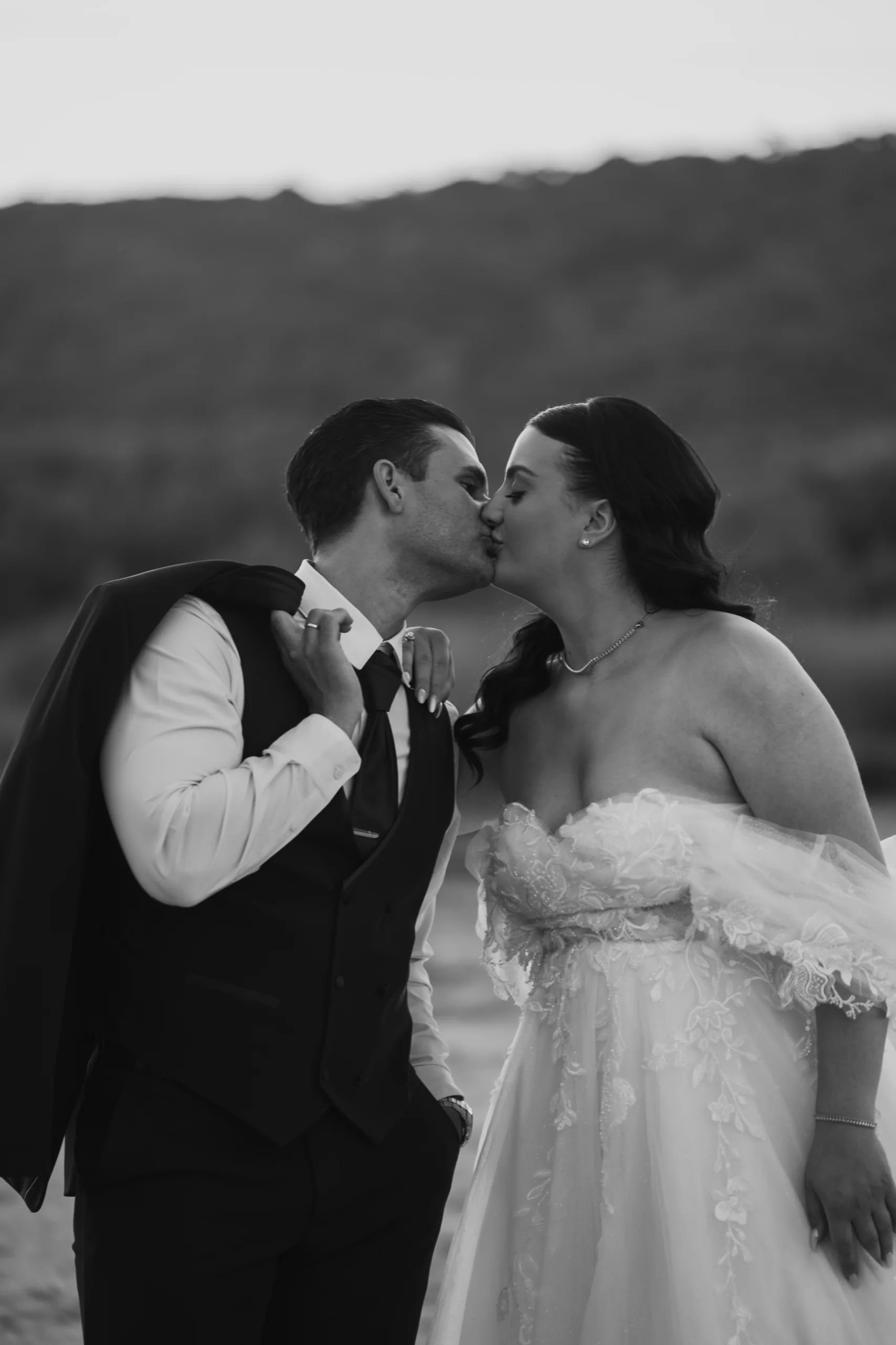 Black-and-white photo of the couple kissing at dusk