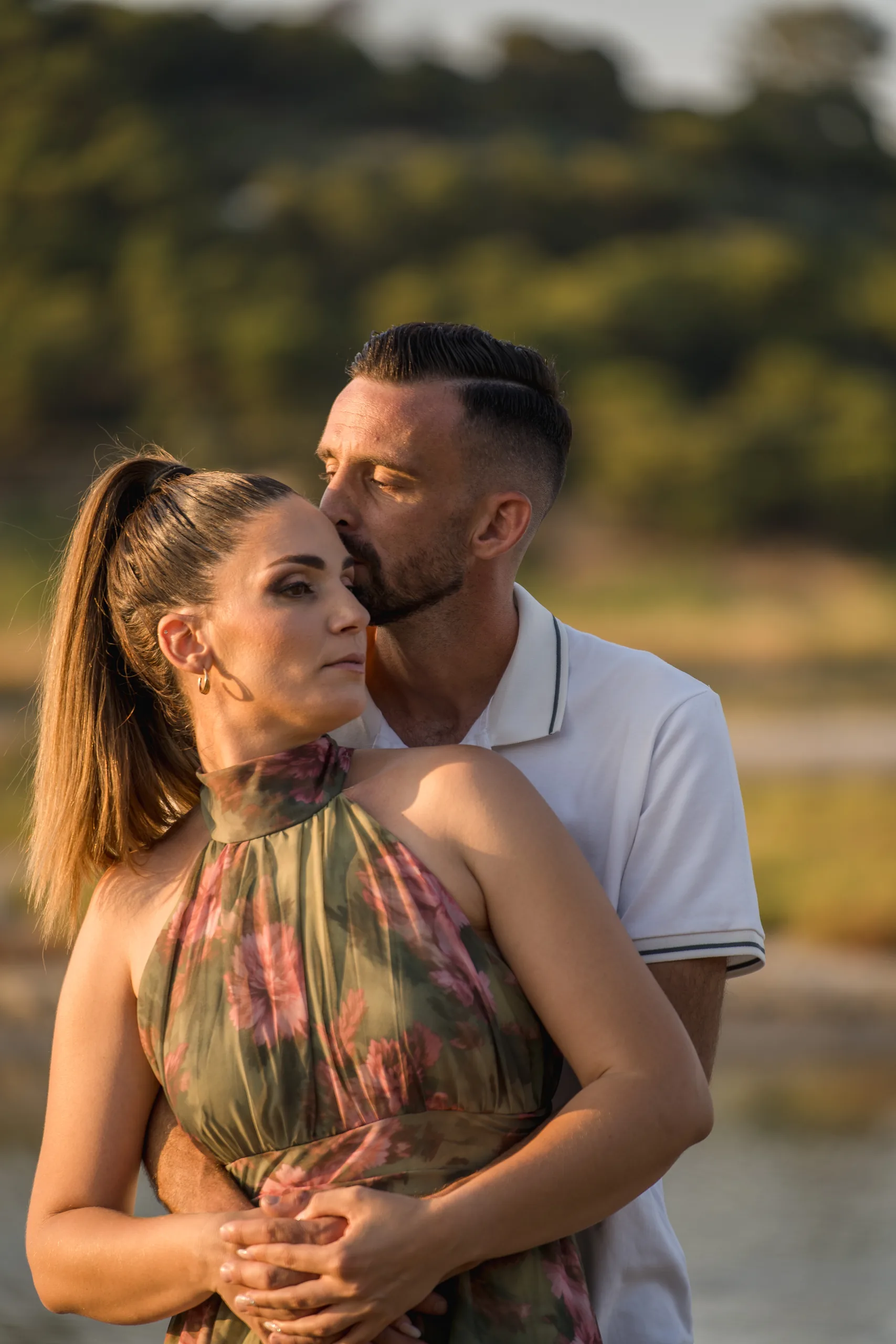 Το ζευγάρι αγκαλιάζεται ανάμεσα στα δέντρα στη χρυσή ώρα