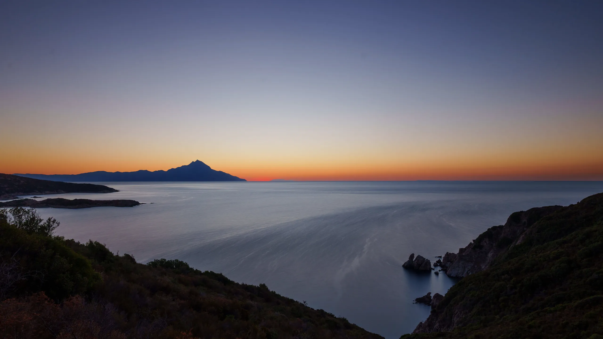Coastline at dusk with a mountain on the horizon