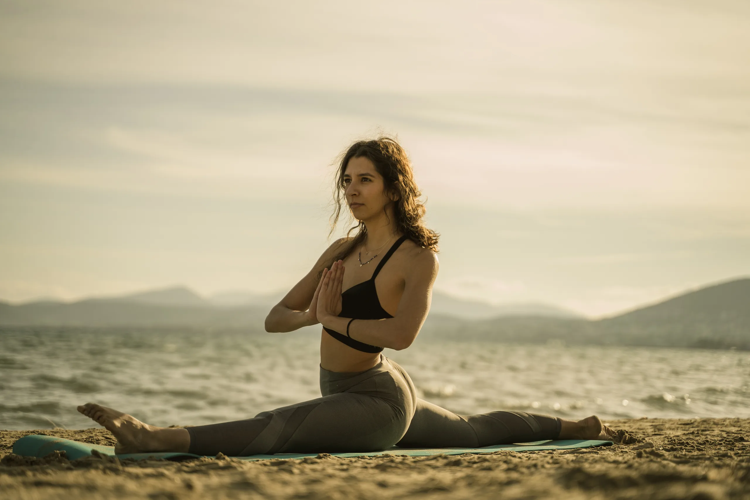 Woman in a yoga pose on the beach at sunset