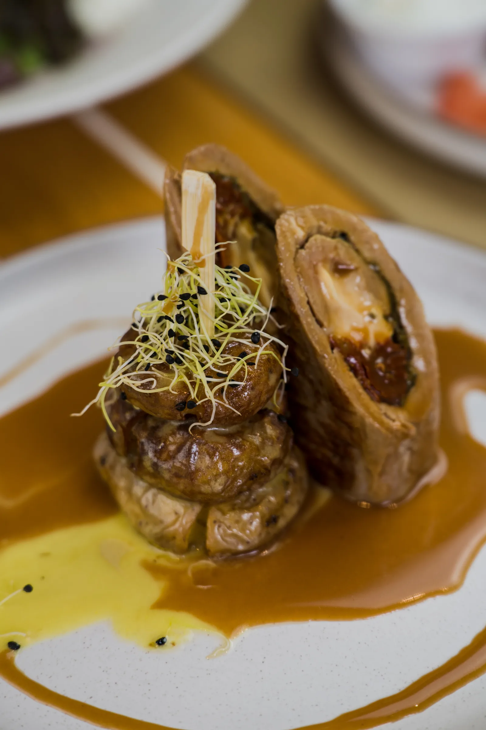 Plated meat roulade with sauce and microgreens