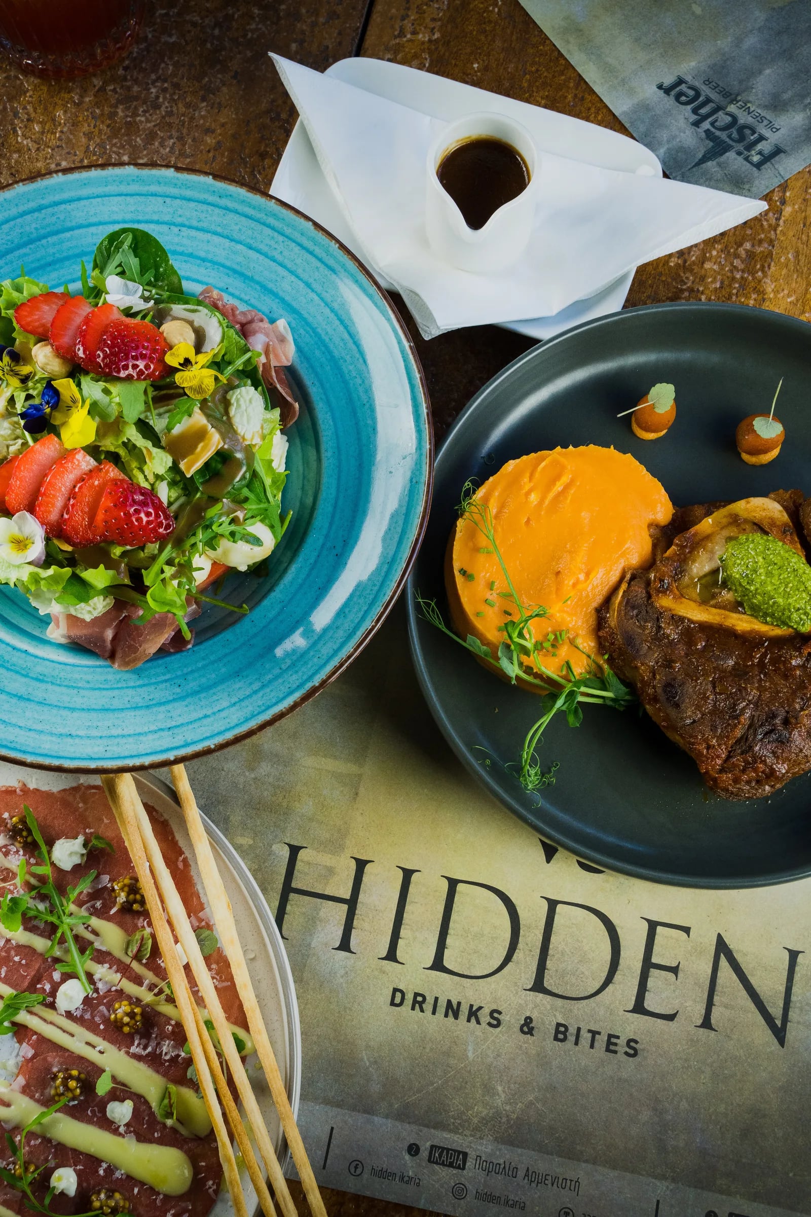 Overhead view of salads and plates at Hidden Drinks & Bites